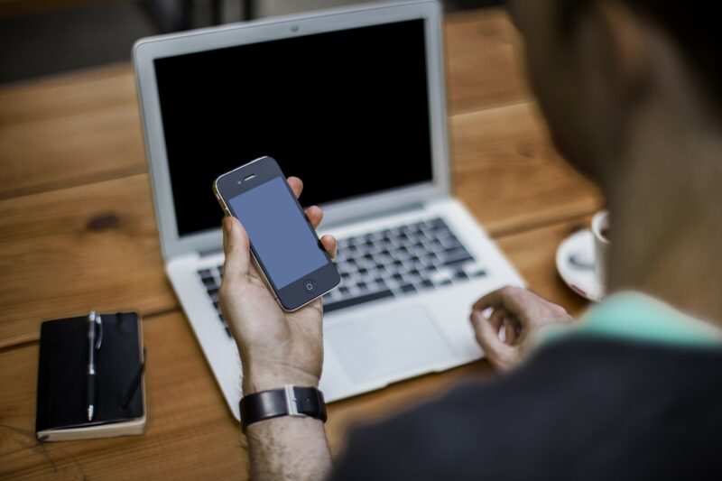 person working on phone and computer